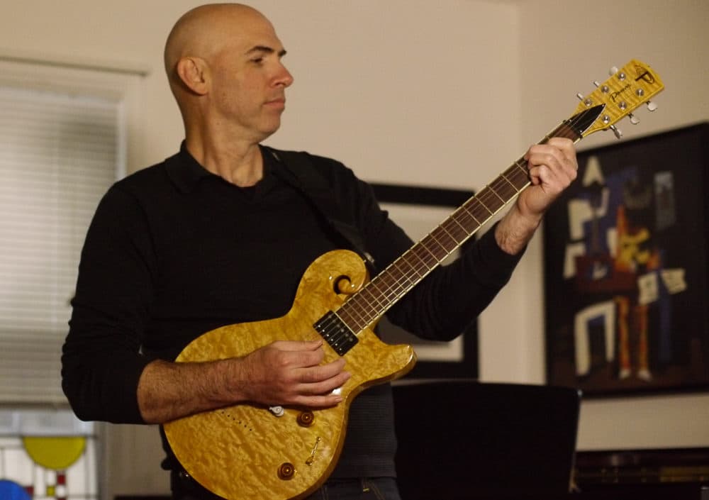 Eric Shimelonis playing an electric guitar custom built by Jay Pawar. (Courtesy of Rebecca Sheir)