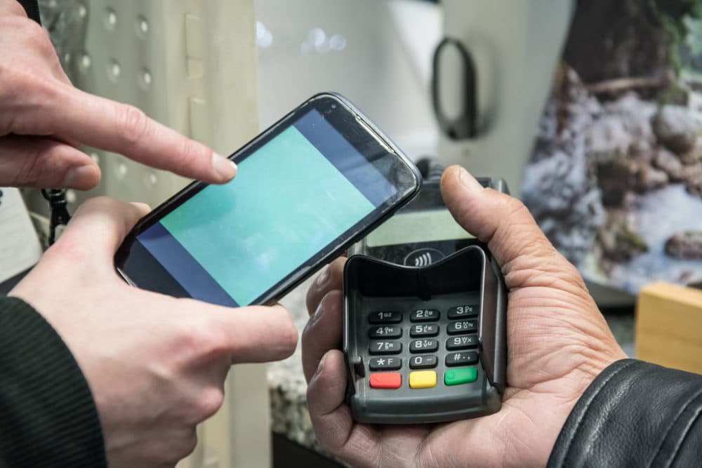 Showing someone how to make a cashless payment. (Getty images)