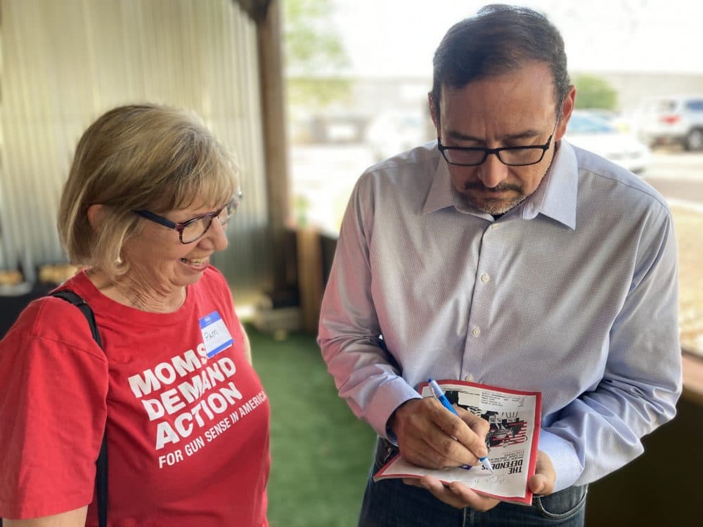 Secretary of State candidate Adrian Fontes, a Democrat, signs a copy of Time magazine for a voter in Tucson, Ariz. Time recently featured Fontes and other candidates running against election deniers in battleground states. (Peter O'Dowd/Here &amp; Now)