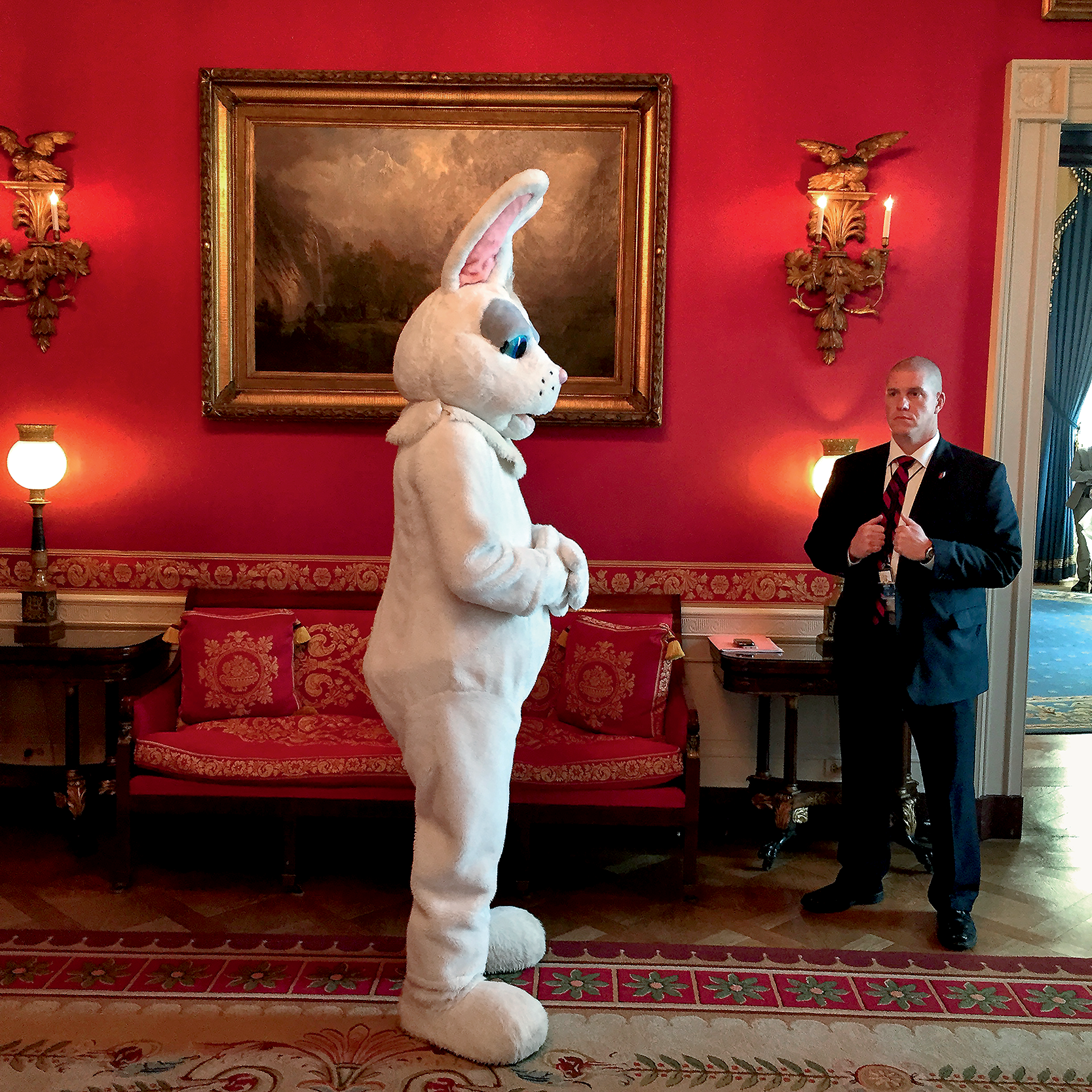 The Easter Bunny waits in the Red Room to enter the adjacent Blue Room to meet the President as a Secret Service agent stands guard before the annual Easter Egg Roll in 2015. Copyright © 2022 by Pete Souza. (Courtesy of Pete Souza)