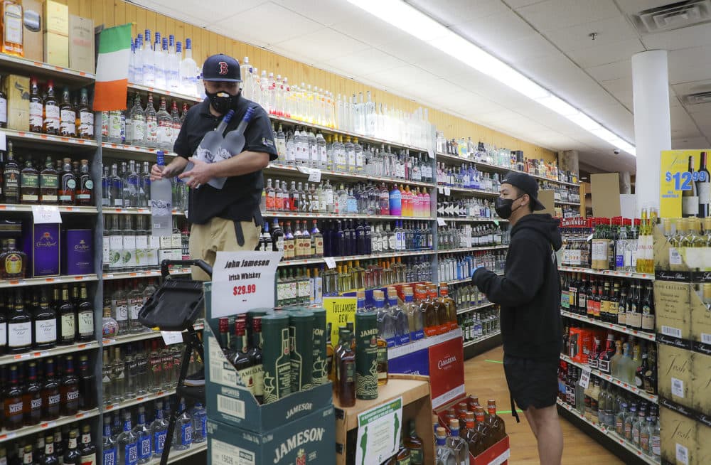 An employee at Supreme Liquor gets down three 1.75 liter bottles of vodka from the top shelf for a customer in its Cambridge in April 2020. (Matthew J. Lee/The Boston Globe via Getty Images)