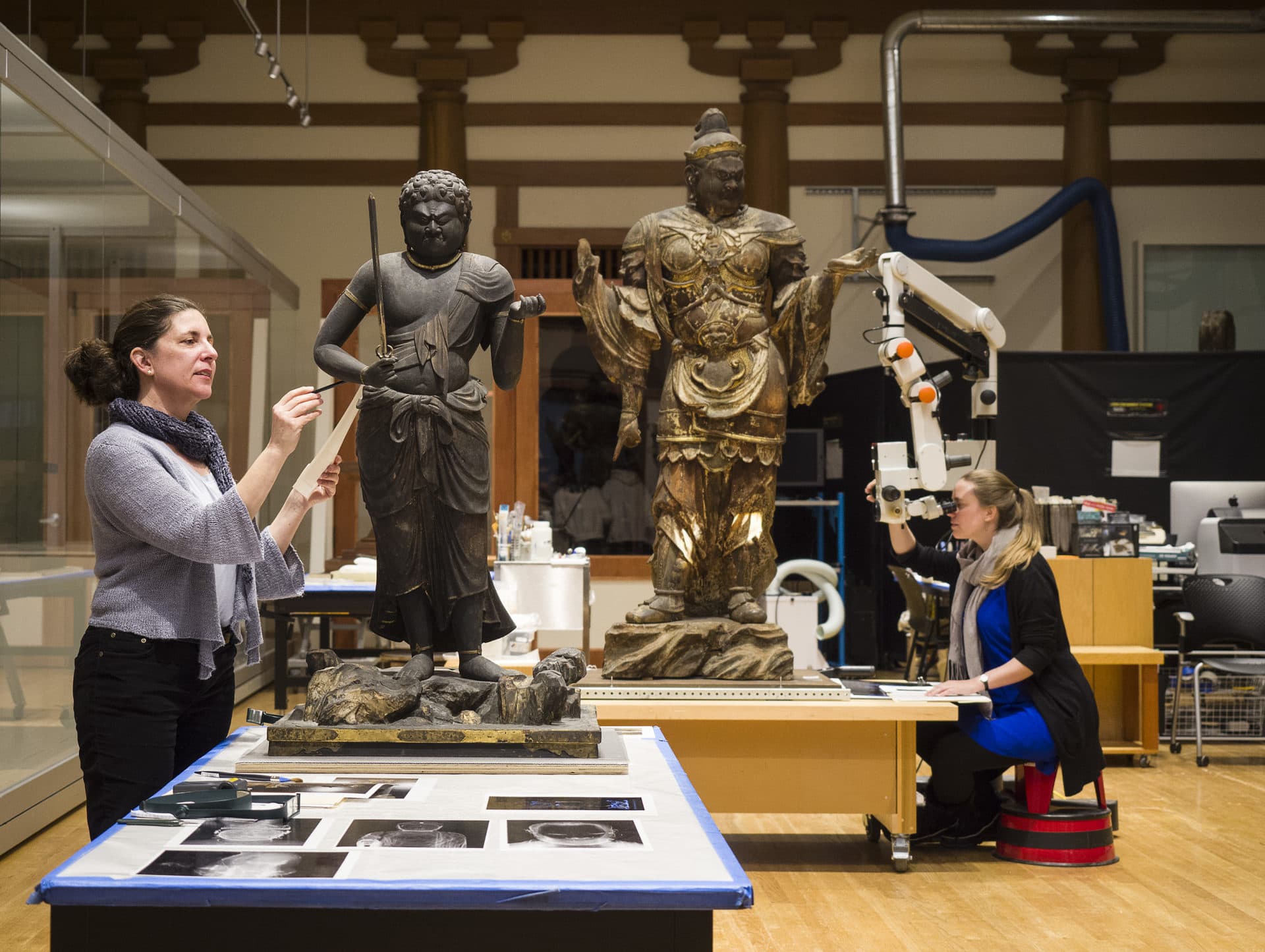 Abby Hykin (left), head of objects conservation, and Eve Mayberger, assistant conservator, examine some of the Japanese Buddhist sculptures as part of Conservation in Action at the MFA. (Courtesy Museum of Fine Arts, Boston)