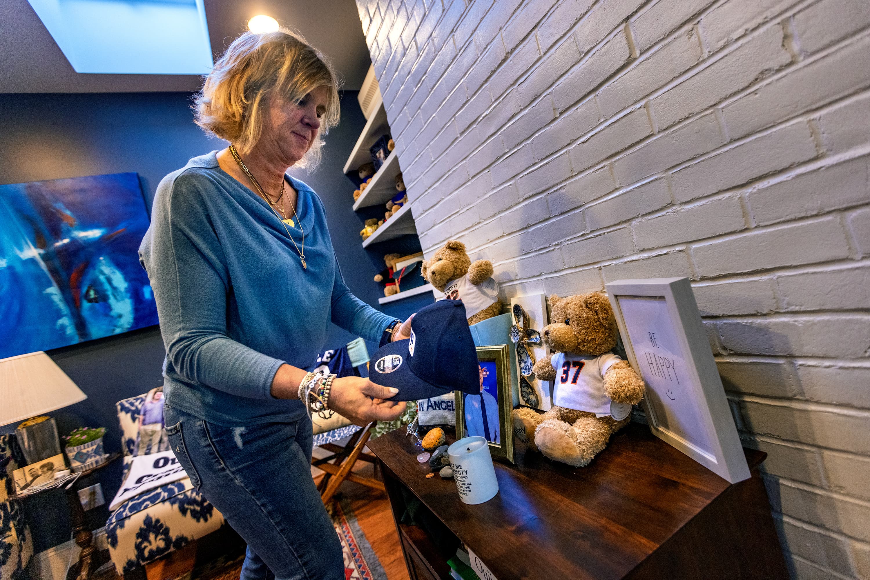 Sally Cioffi places a baseball cap on a memorial to her 22-year-old son, Sam, who died after taking a Percocet laced with fentanyl he bought through social media. (Jesse Costa/WBUR)
