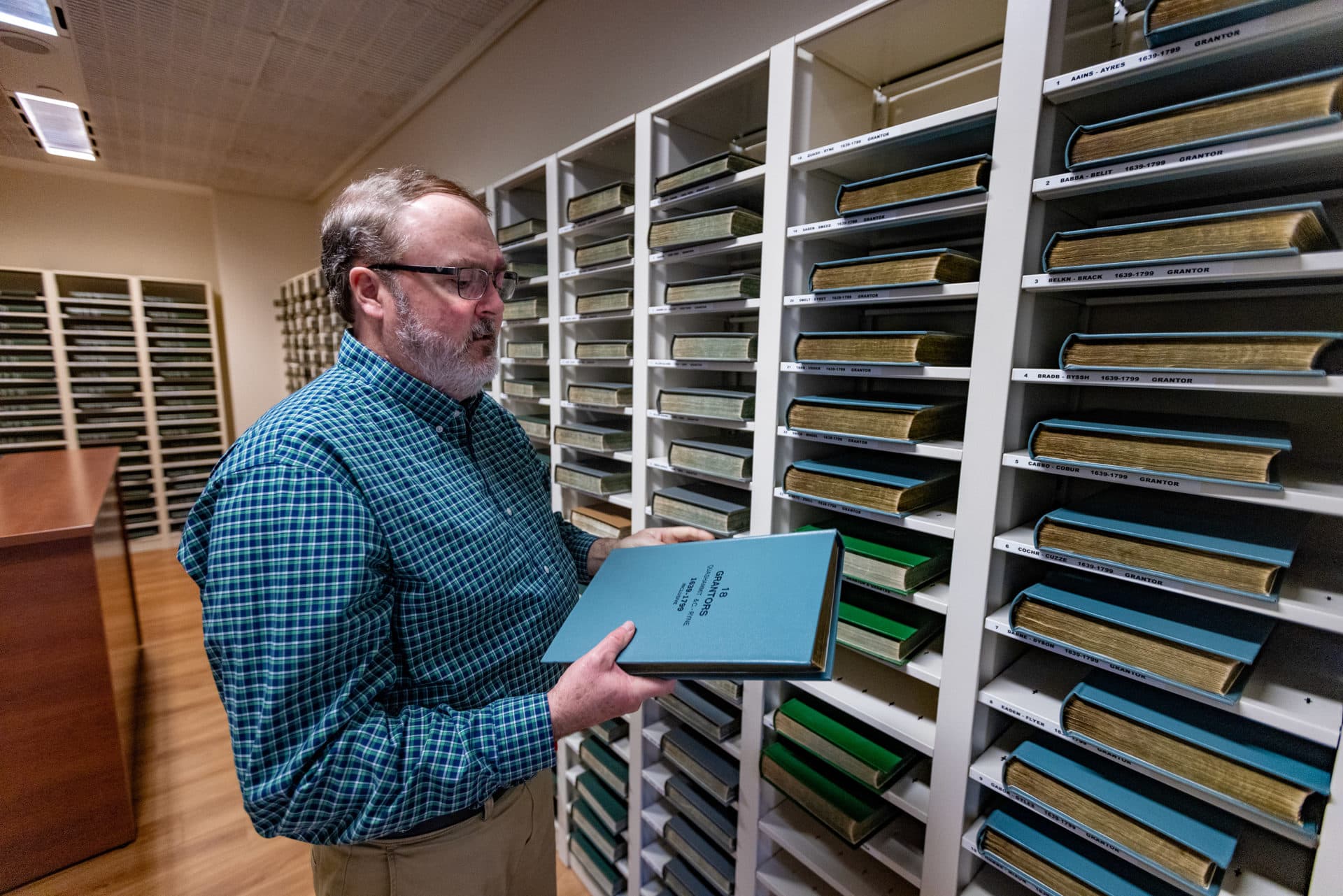 Tom Ryan, first assistant register at the Suffolk Registry of Deeds, pulls out records containing property listings for famed revolutionary Paul Revere. (Jesse Costa/WBUR)