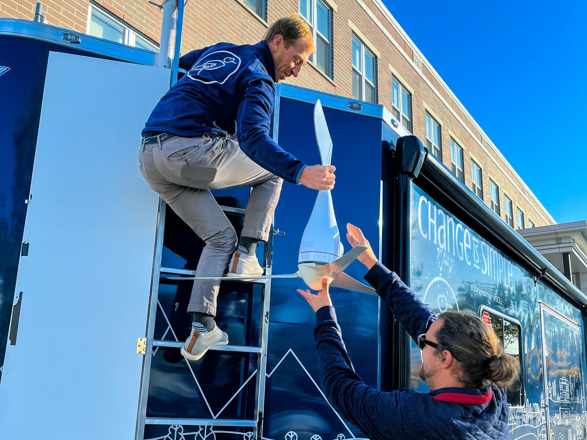 Change is Simple's co-founder Patrick Belmonte installs a wind turbine atop the mobile learning lab in front of Paul Revere Elementary. (Aimee Moon/WBUR)