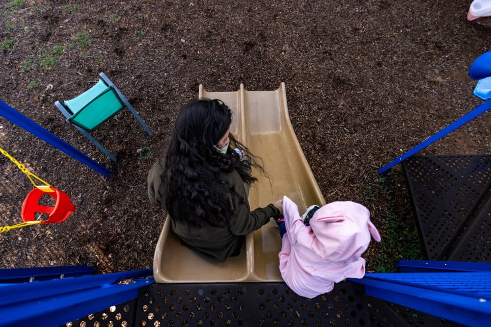 Paula plays on a slide with her daughter. (Jesse Costa/WBUR)
