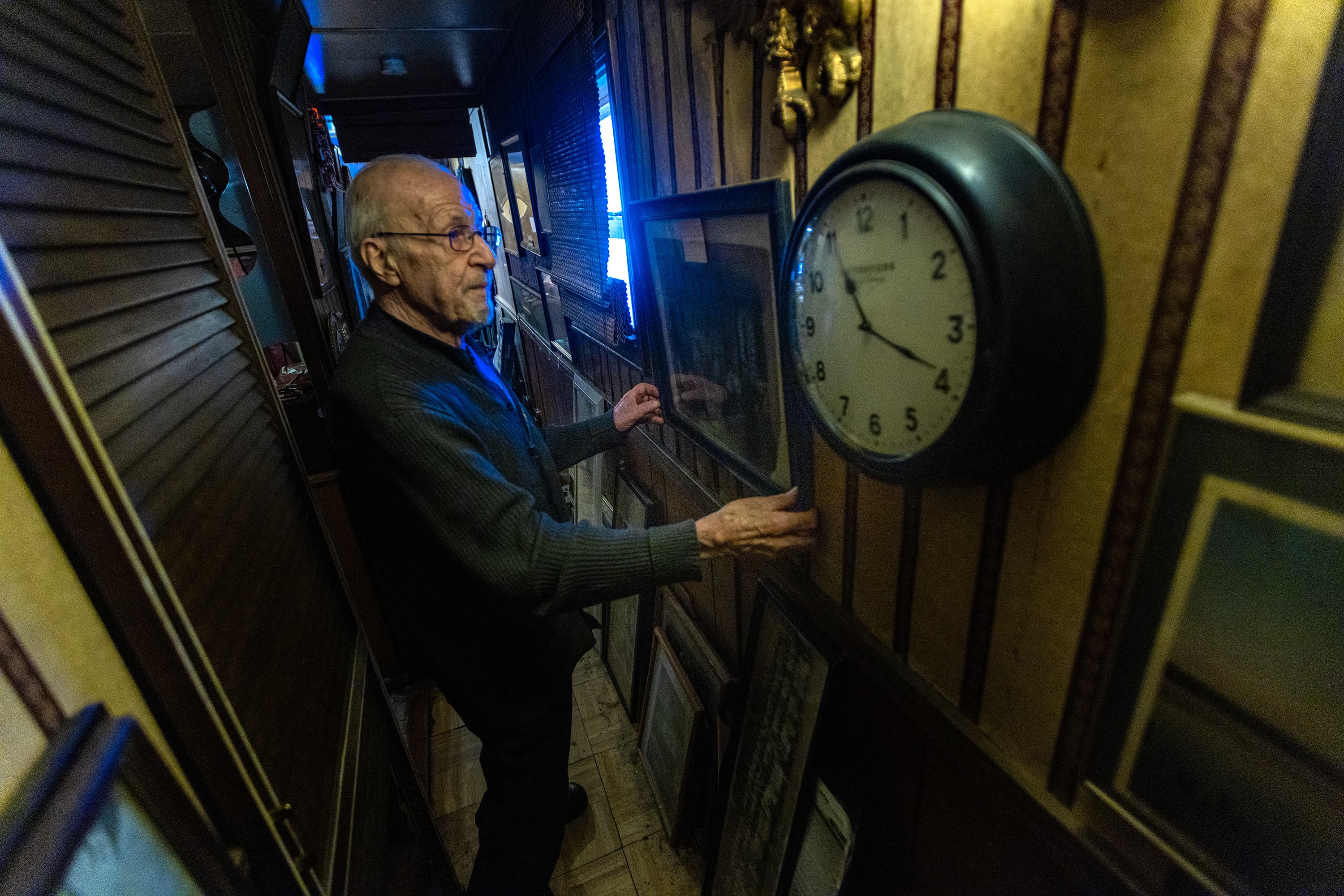 John Piazza adjusts a picture frame in his trailer at Lee’s Trailer Park in Revere. (Jesse Costa/WBUR)