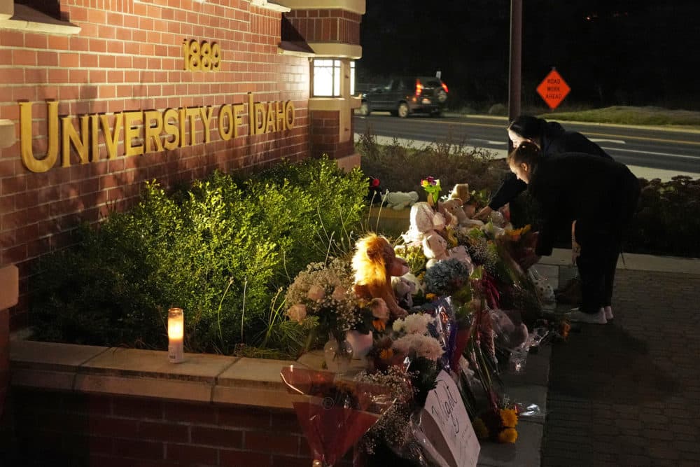 Two people place flowers at a growing memorial in front of a campus entrance. (Ted S. Warren/AP)