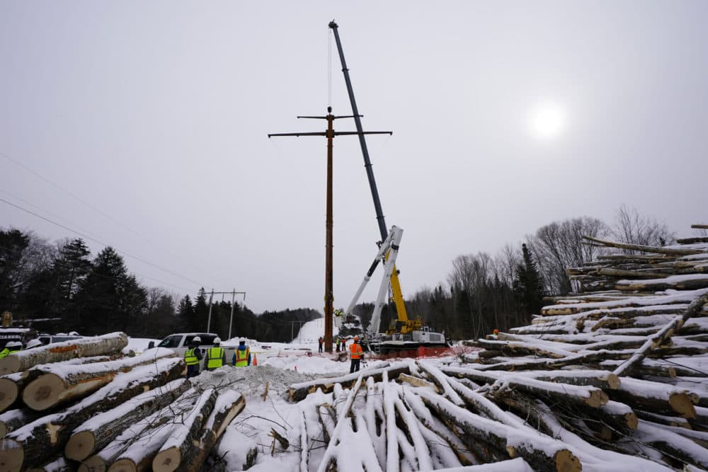 Workers connect a section of the first pole of Central Maine Power's controversial hydropower transmission corridor, Feb. 9, 2021, near The Forks, Maine. (Robert F. Bukaty/AP File)