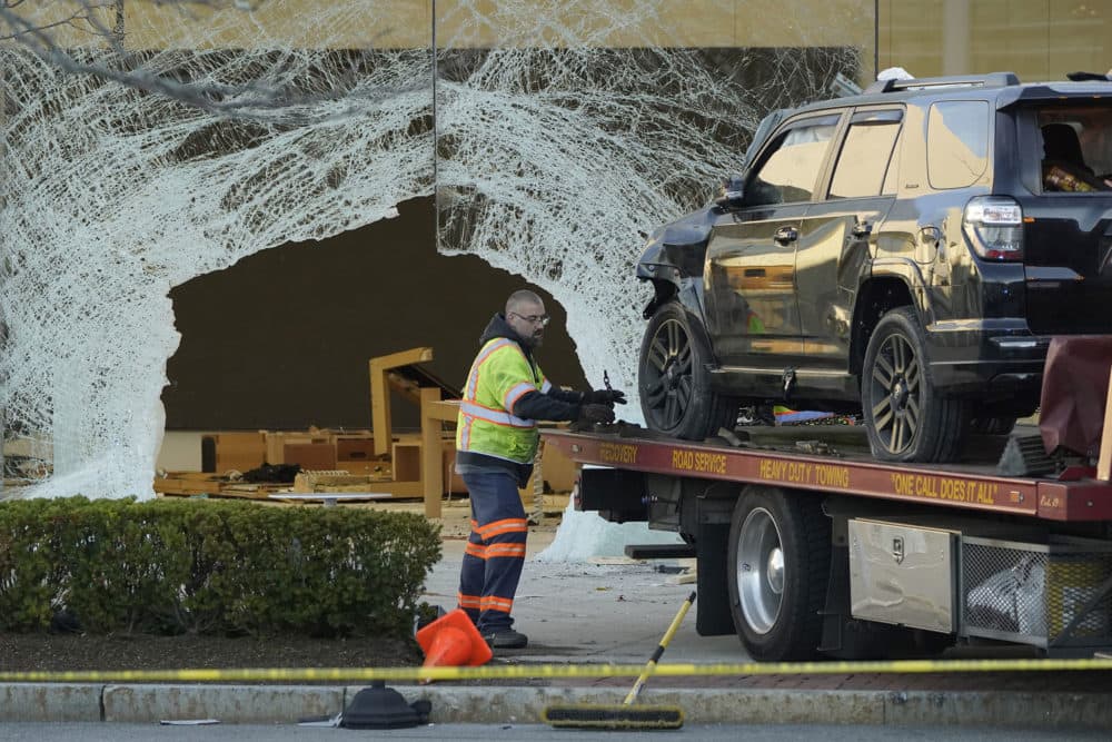 A worker secures a damaged SUV to a flatbed tow truck outside the Apple store in Hingham on Monday, Nov. 21. (Steven Senne/AP)