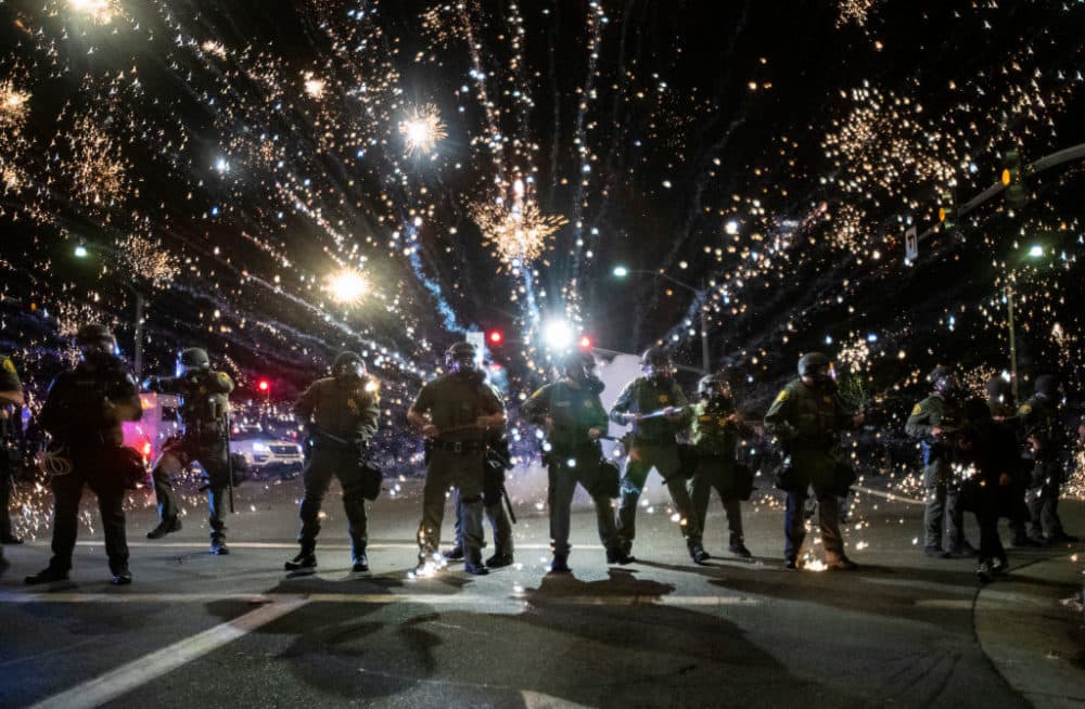 Orange County Sheriff deputies maintain a police block as a firecracker thrown by a protester explodes behind them during a protest against the Minneapolis police killing of George Floyd during the coronavirus pandemic on May 30, 2020 in Santa Ana, California. (Gina Ferazzi / Los Angeles Times via Getty Images)