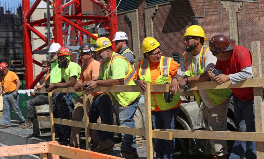 Construction workers line up on a safety rail at the site watched the topping off ceremony as Samuels & Associates tops off Parcel 12, an air-rights project being built over the Massachusetts Turnpike at Newbury and Boylston streets and Massachusetts Avenue in Boston on June 7, 2022. (David L. Ryan/The Boston Globe via Getty Images)