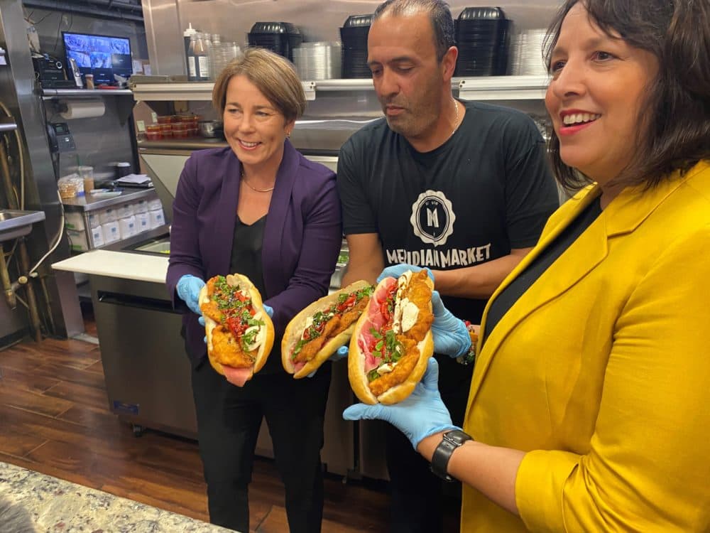 Maura Healey, the Democratic candidate for governor, and her running mate, Kim Driscoll, pose with restaurant owner Freddy Noviello at Meridian Street Market in East Boston. (Anthony Brooks/WBUR)