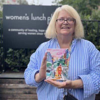Kim Collins is a longtime Women's Lunch Place client who now teaches art therapy classes there. She's holding her painting that will serve as the artwork for the shelter's 2022 Holiday Card campaign. (Courtesy Women's Lunch Place)