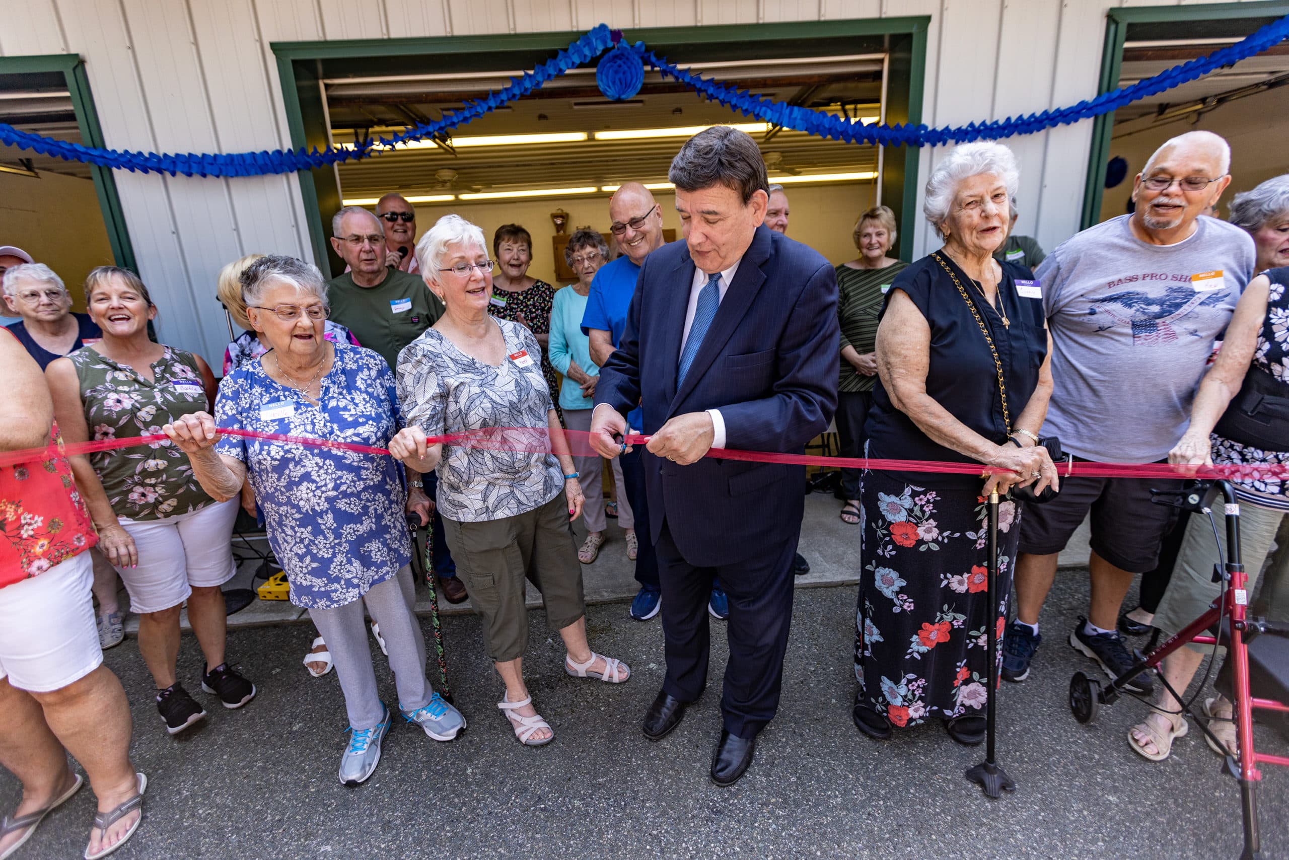 Massachusetts state Sen. Marc Pacheco, who led the passage of the state's mobile home law in the 1990s, cuts a ribbon celebrating the Royal Crest residents' purchase of the property. (Jesse Costa/WBUR)