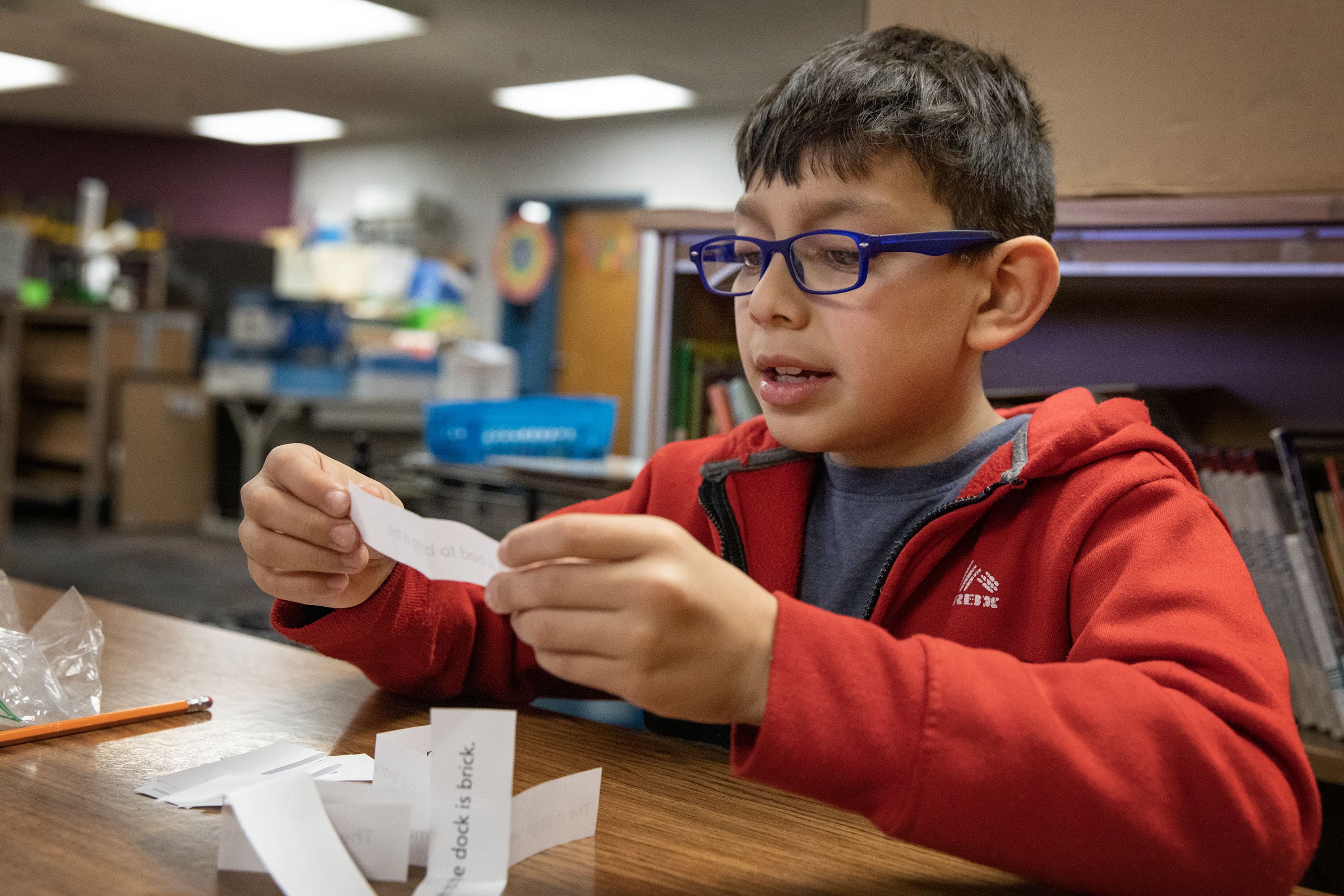 Third grader Matthew Pacheco Hernandez in Audra Lessard's small group reads sentences from strips of paper as quickly as he can. (Robin Lubbock/WBUR)