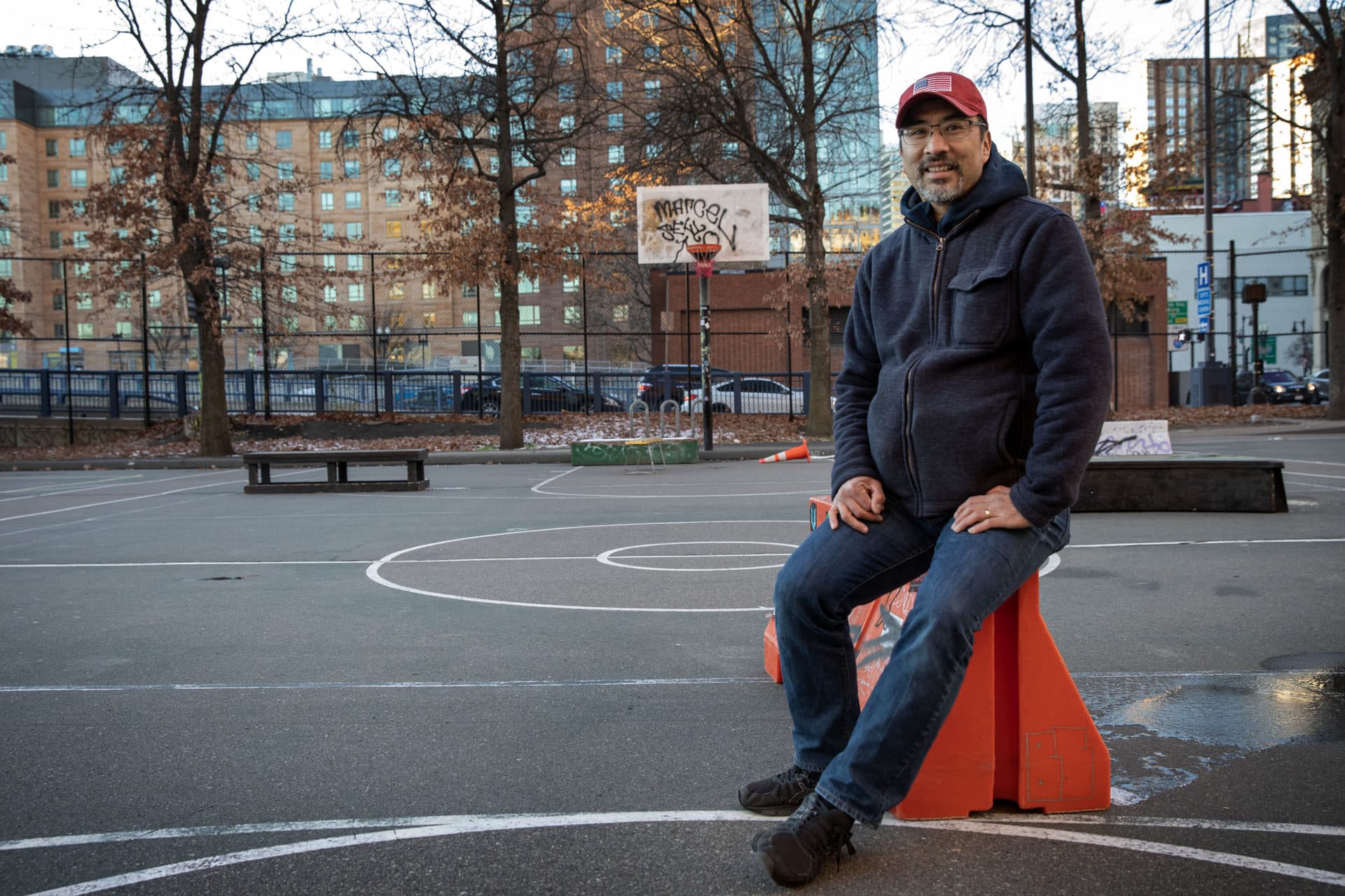 Russell Eng, president of Friends of Reggie Wong Park, stands at the center of the park on a winter evening. (Robin Lubbock/WBUR)