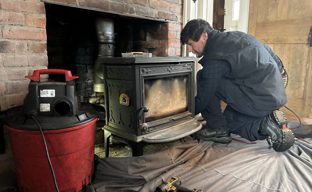 Christopher Britt cleans the Wilsons' chimney. (Mara Holpamazian/NHPR)