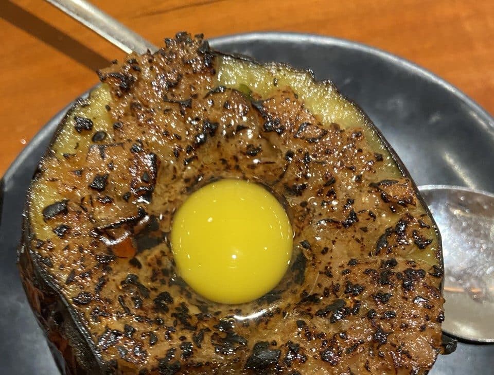 Berinjela frita coberta com carne de porco miso picante e um ovo de codorna cru no Raku em Nova York.  (Kathy Gunst/Aqui e Agora)