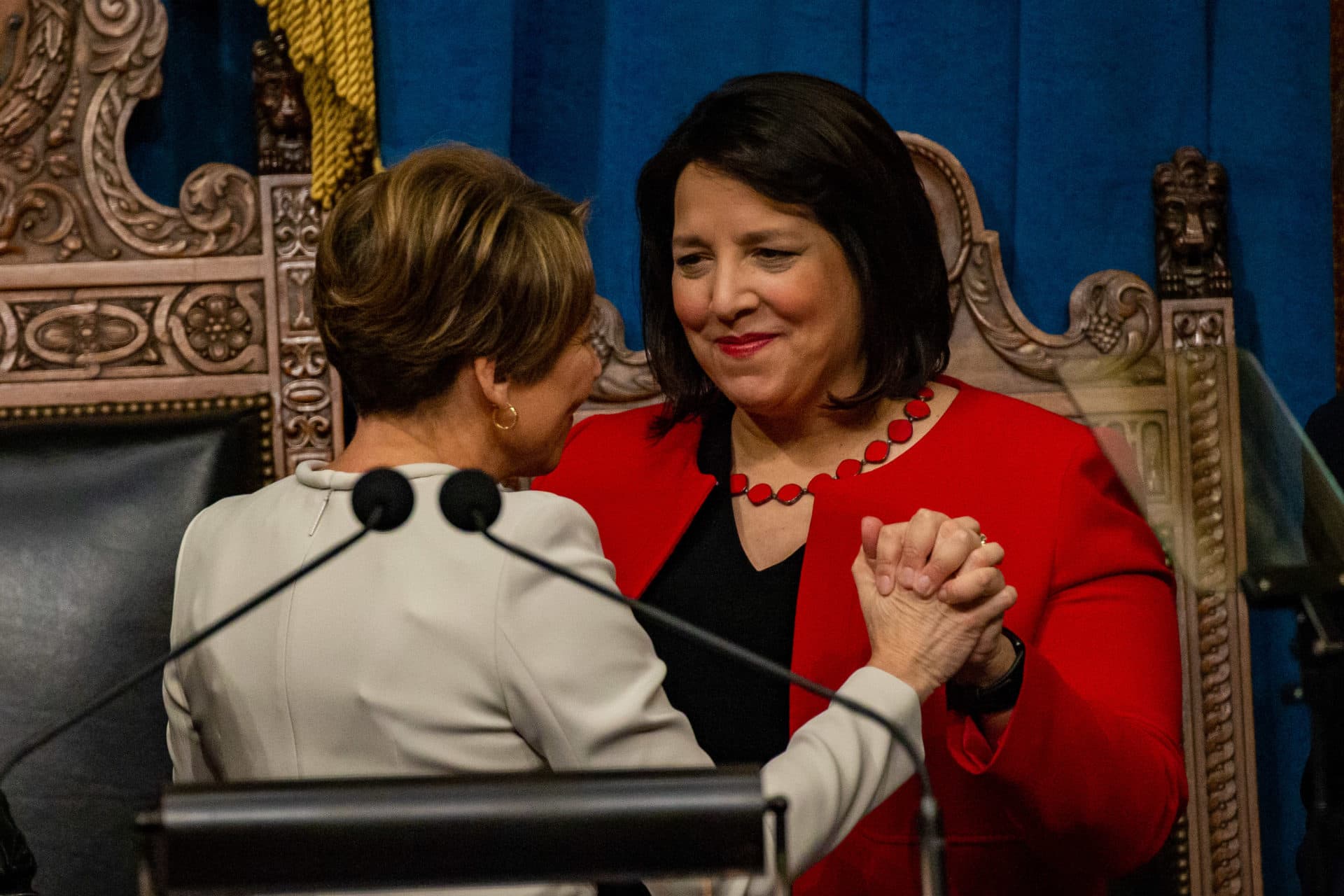 Maura Healey and Kim Driscoll hold hands after Healey is sworn in as the new governor of Massachusetts. (Jesse Costa/WBUR)