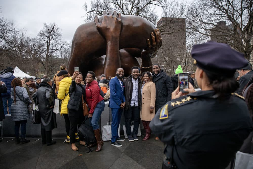 Attendees at the ceremony celebrate and takes selfies in front of the newly unveiled Embrace sculpture on Boston Common. (Robin Lubbock/WBUR)