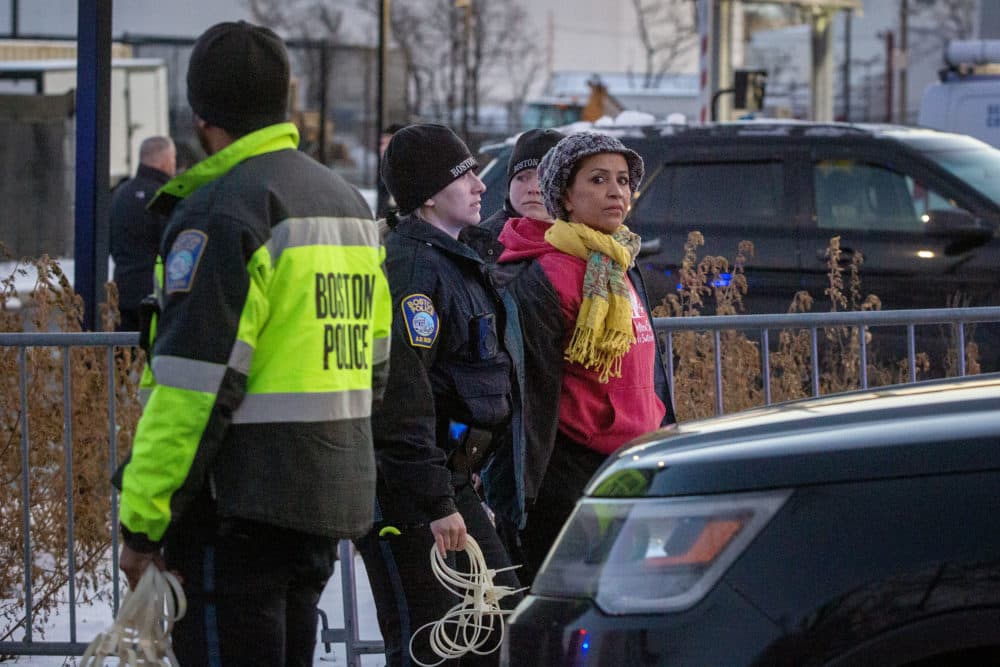 Police walk an Extinction Rebellion protester to a police vehicle, following a protest at the site of the East Boston electrical substation. (Robin Lubbock/WBUR)