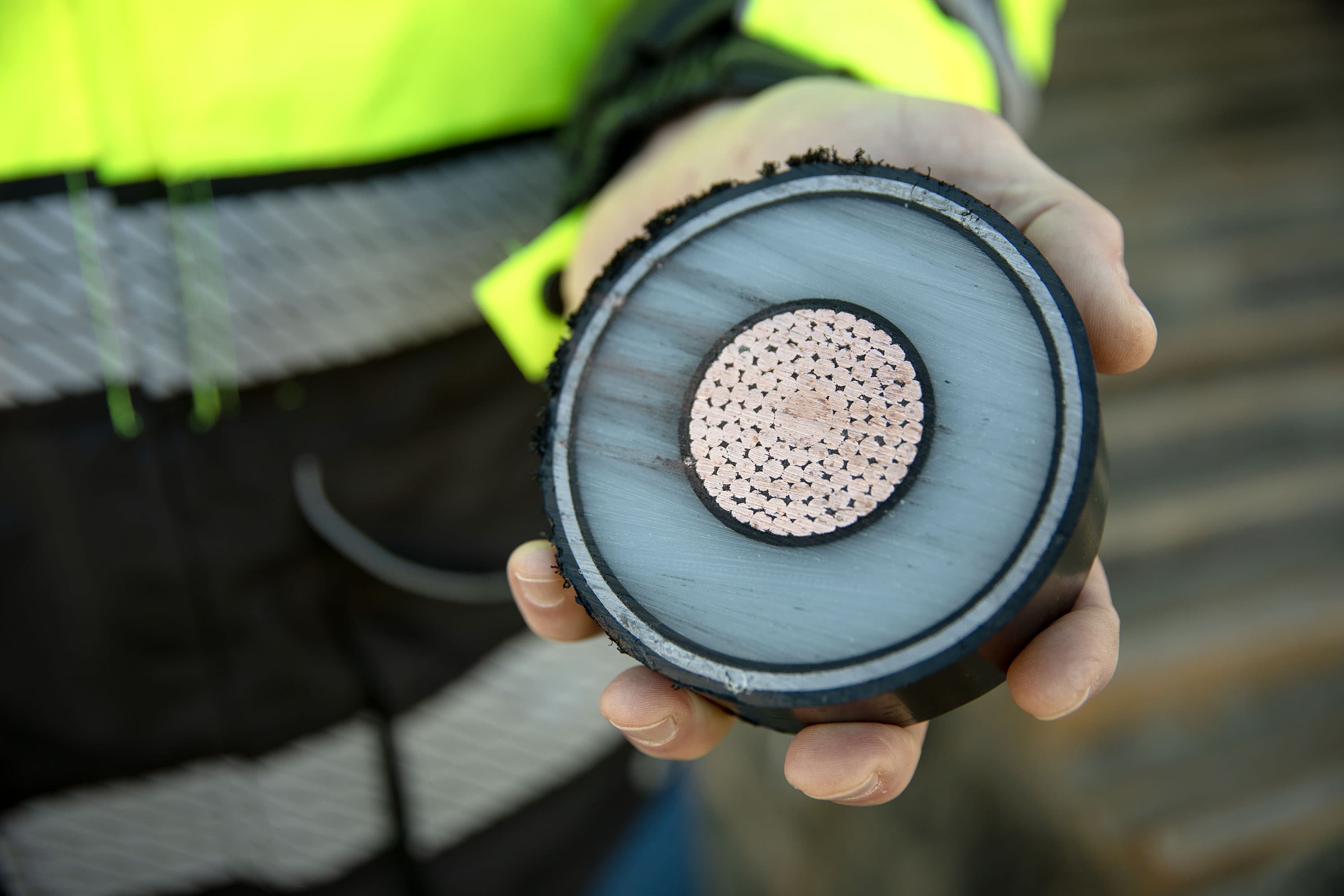 Vineyard Wind's Ian Campbell holds a cross section of one of the three power lines carried inside the landfall cables at Covell's Beach. (Robin Lubbock/WBUR)