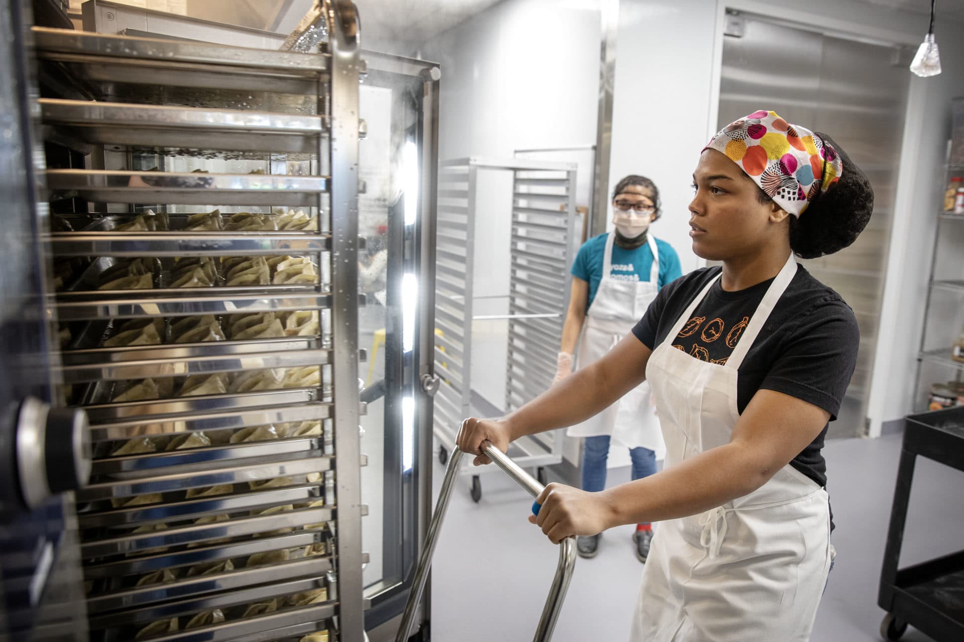 Angelle Castro gently pulls trays of dumplings out of an oven at Mei Mei. (Robin Lubbock/WBUR)