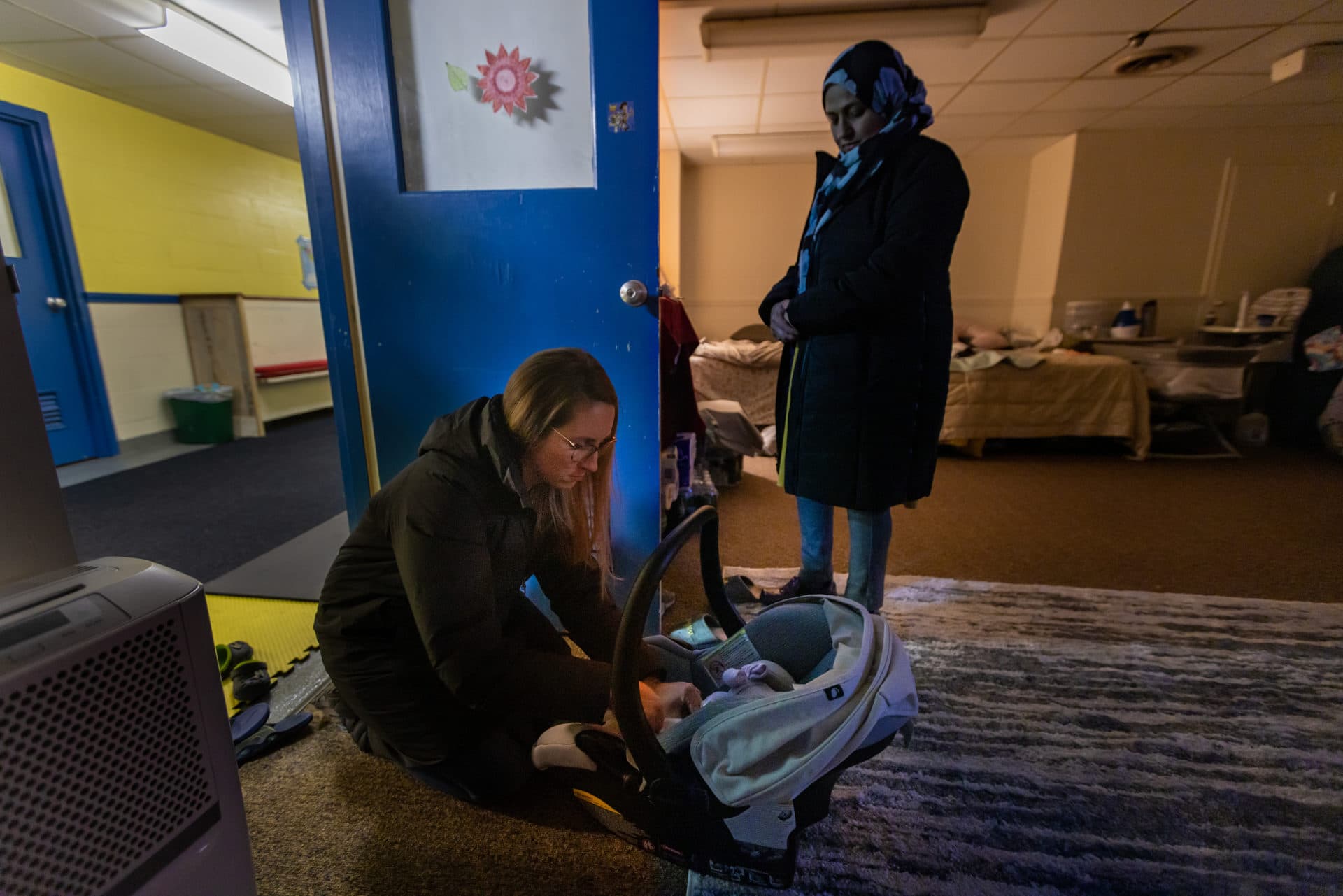 Chelsea Mercer, wife of Rev. Jarred Mercer, places Gulalai's daughter Nadya in a car seat to take the two of them to an appointment at the pediatrician. (Jesse Costa/WBUR)