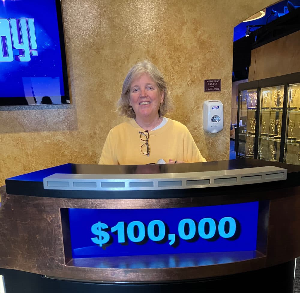 The author, Rev. Anne Gardner, posing behind a contestant podium on display in an exhibit area adjacent to the set of “Jeopardy!” after watching a live taping of the show in Los Angeles, 2023. (courtesy Anne Gardner)