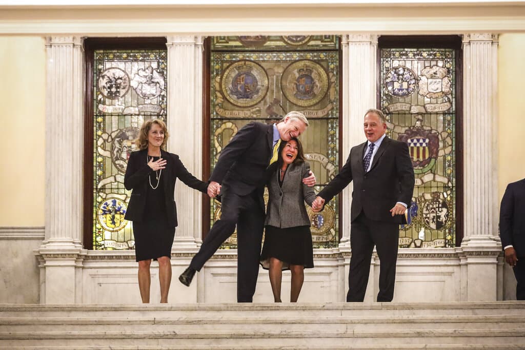 Massachusetts Gov. Charlie Baker hugs Lt. Gov. Karyn Polito before walking down the Grand Staircase with his wife Lauren Baker, left, and Polito's husband, Steve Rodolakis, as the governor took his last walk through the State House. (Erin Clark/The Boston Globe via pool)