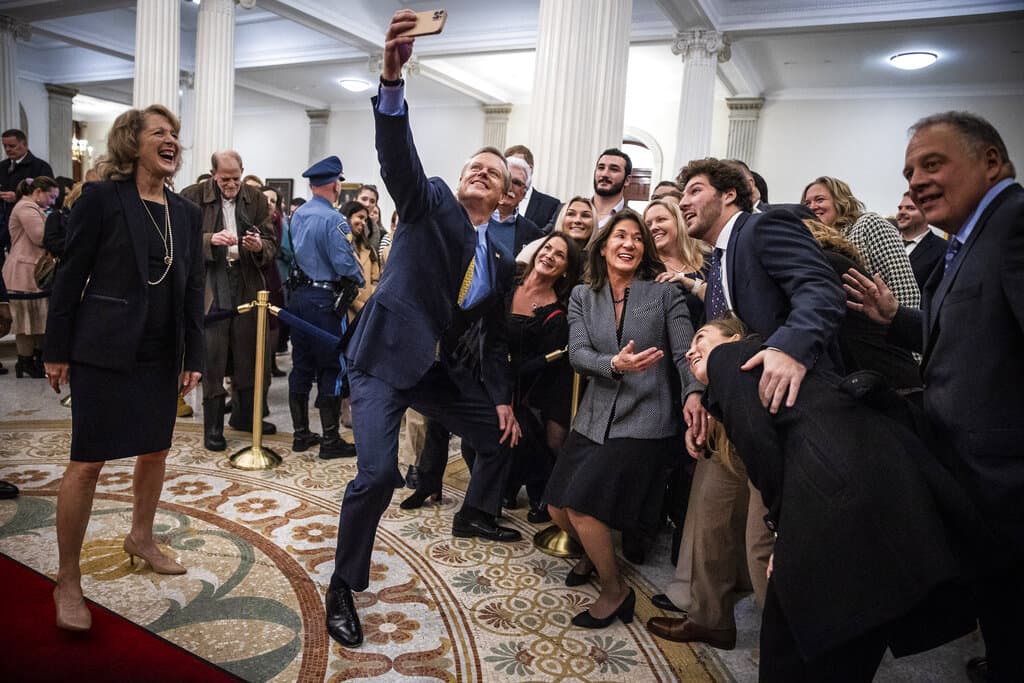 Massachusetts Gov. Charlie Baker takes a selfie with attendees while taking his last walk through the State House. (Erin Clark/The Boston Globe via pool)