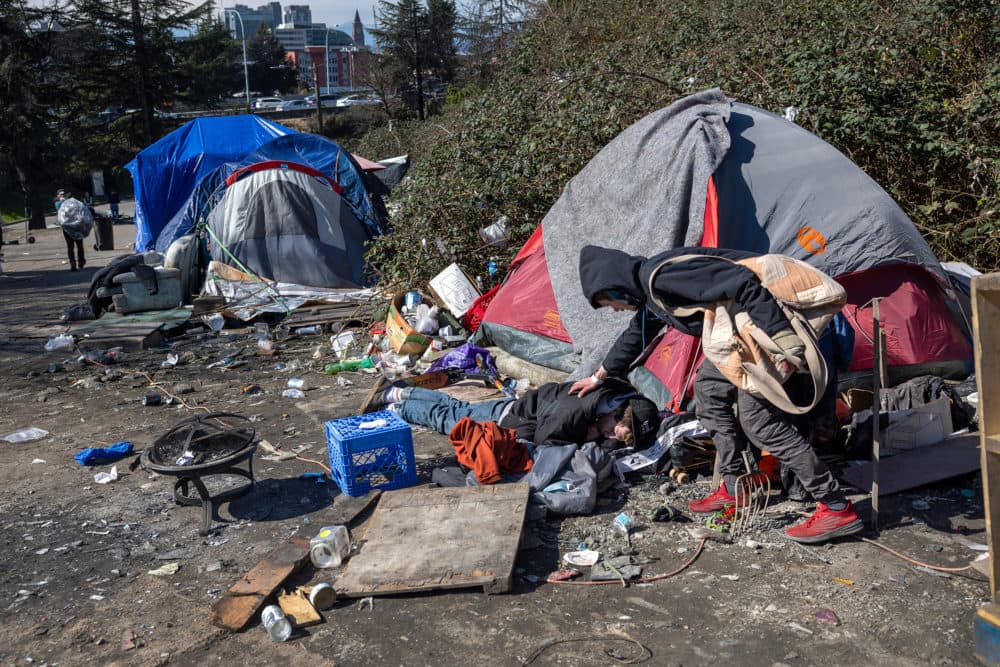 A homeless man checks on a friend who had passed out after smoking fentanyl at a homeless encampment on March 12, 2022 in Seattle, Washington. (John Moore/Getty Images)