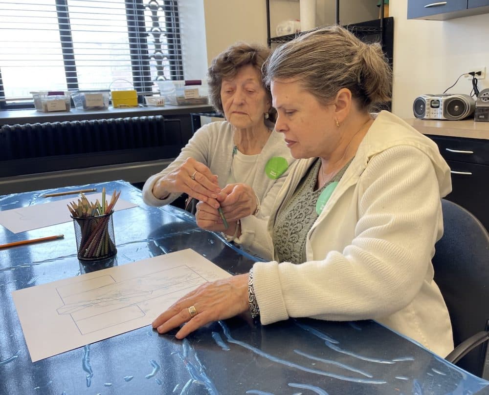 Edythe Burd helps her friend, Mary Tometich (right), decorate a paper kimono during a visit to the Frist Art Museum. (Blake Farmer WPLN News)