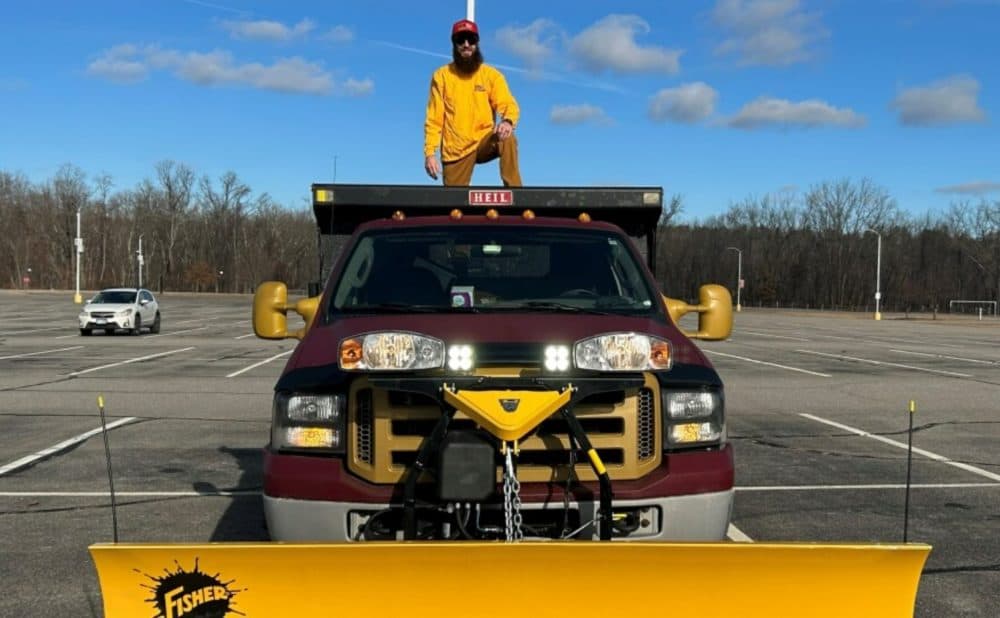Harold Davis stands on his snow plow truck, which he bought this fall. (Mara Hoplamazian/NHPR)