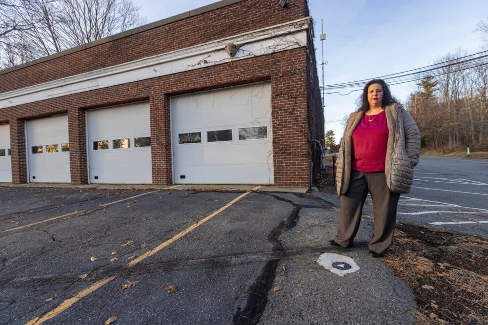 Stow Town Administrator Denise Dembroski, stands in front of the old Stow fire station, the origin of the PFAS contamination, in the town center. (Jesse Costa/WBUR)