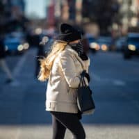 A woman covers her face from the bitter cold wind as she crosses Boylston Street in Copley Square. (Jesse Costa/WBUR)