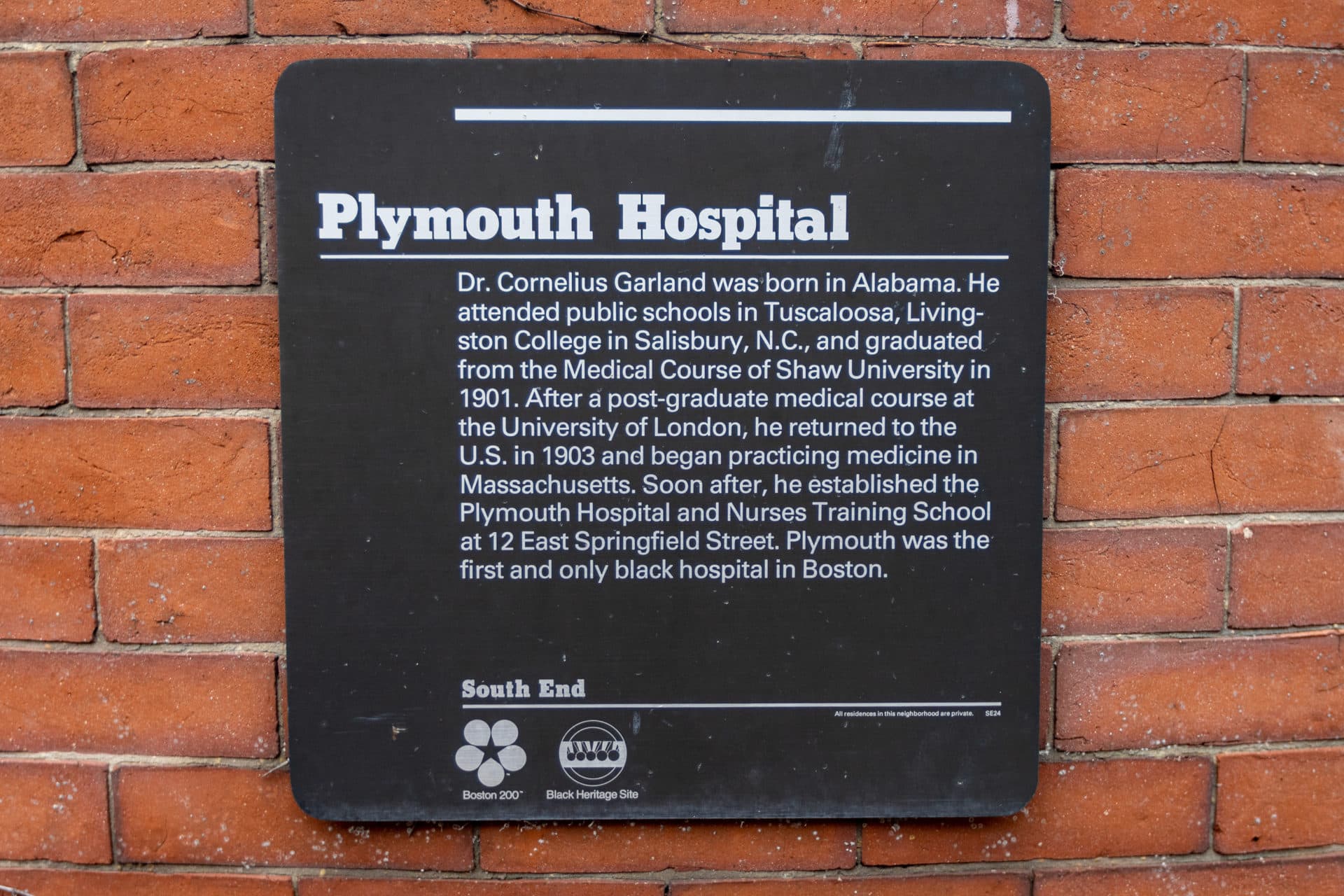 A sign on the exterior of 12 East Springfield Street noting that the building was the location of Plymouth Hospital, the first and only Black hospital in Boston. (Jesse Costa/WBUR)