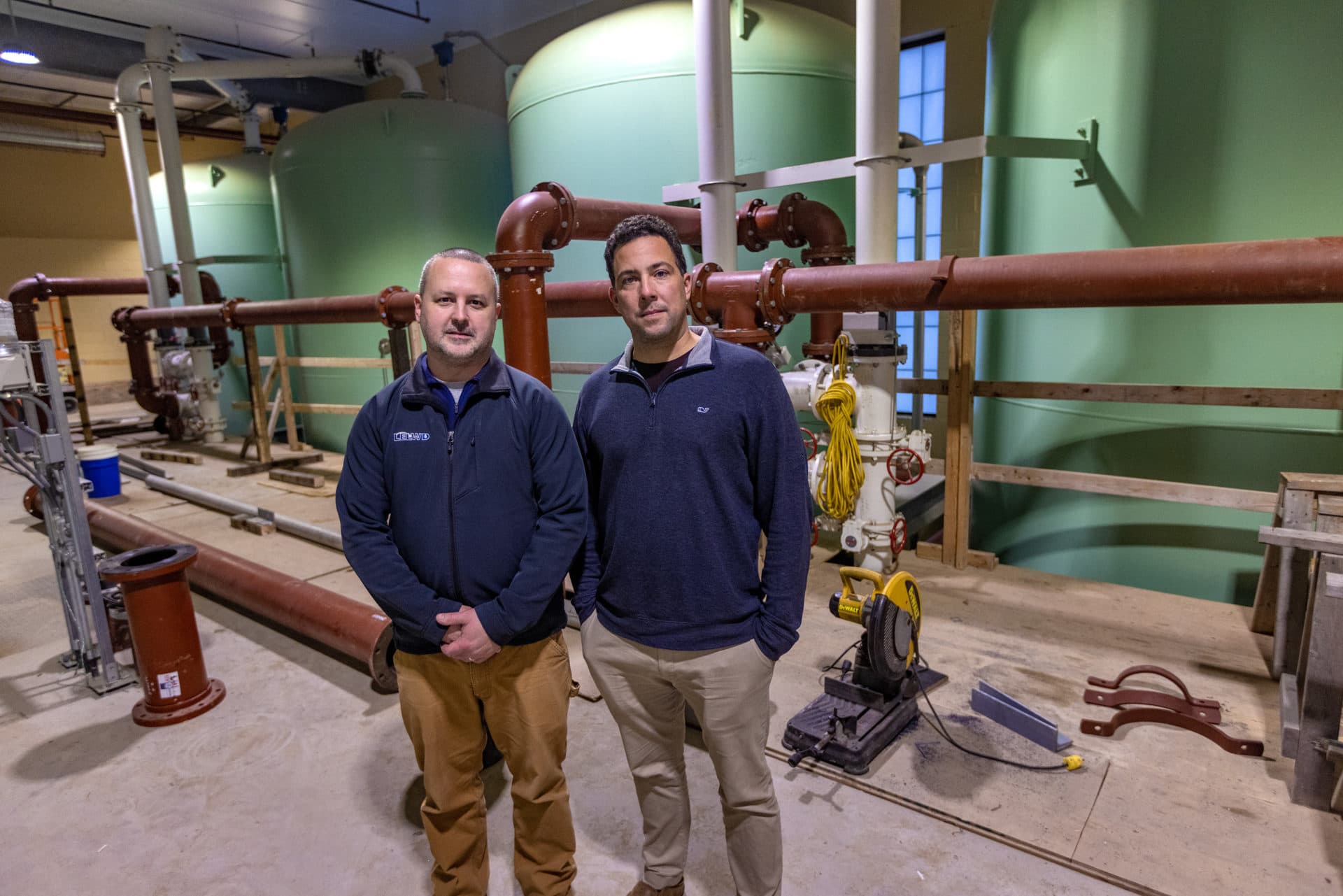 Littleton Electric Light and Water Department Water &amp; Sewer Superintendent Corey Godfrey and general manager Nick Lawler, standing in the new water treatment facility in front of the water filtering tanks. (Jesse Costa/WBUR)