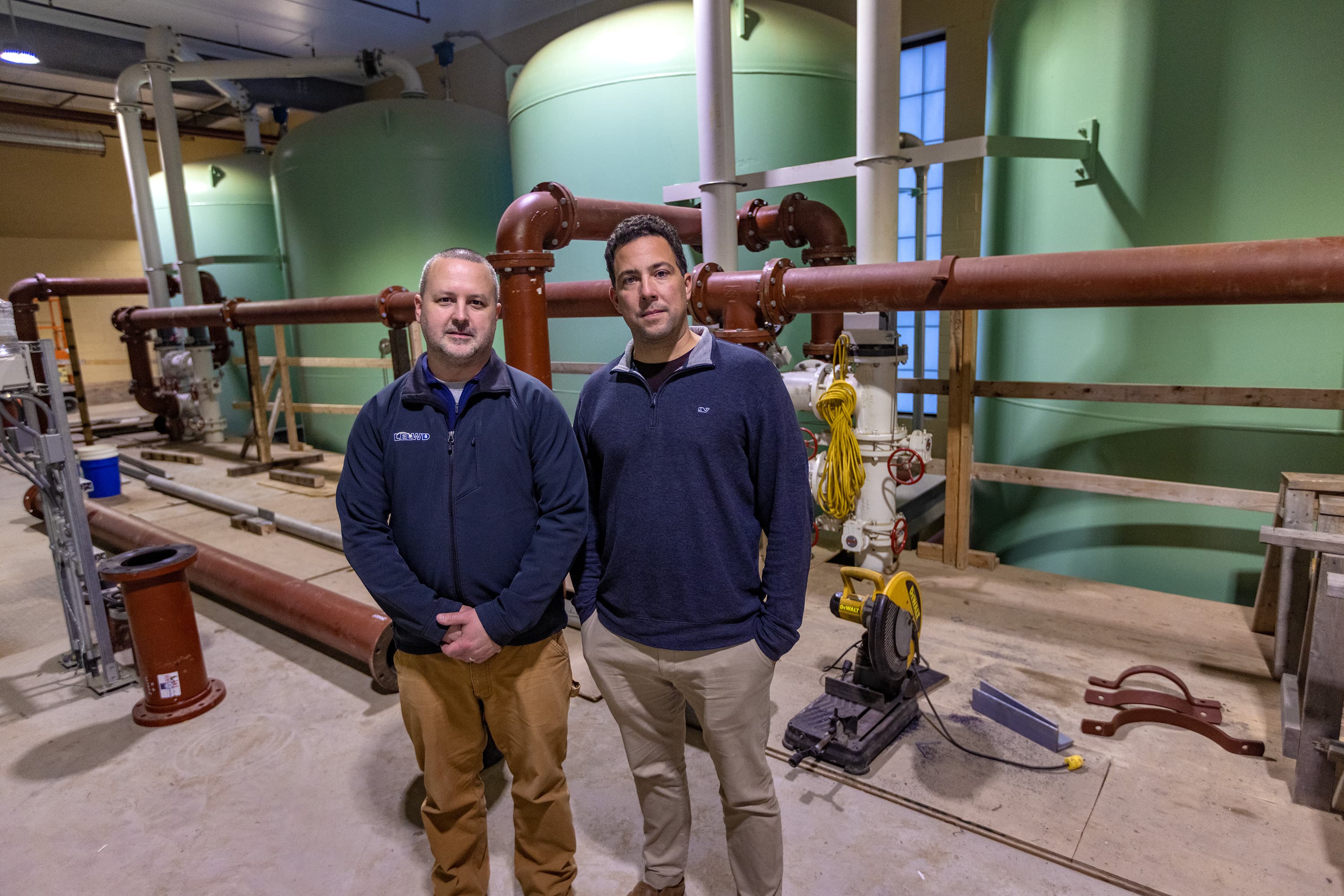 Littleton Electric Light and Water Department Water & Sewer Superintendent Corey Godfrey and general manager Nick Lawler, standing in the new water treatment facility in front of the water filtering tanks. (Jesse Costa/WBUR)