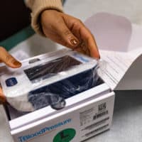 Prenatal digital wellness advocate Briana Rodrigues removes the cellular blood pressure monitoring system from its packaging. The monitor sends the data from each reading directly to Boston Medical Center for health workers to review. (Jesse Costa/WBUR)