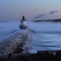 A man walks on sea wall near Spring Point Ledge Light, Saturday, Feb. 4, 2023, in South Portland, Maine. The morning temperature was about -10 degrees Fahrenheit. (Robert F. Bukaty/AP)