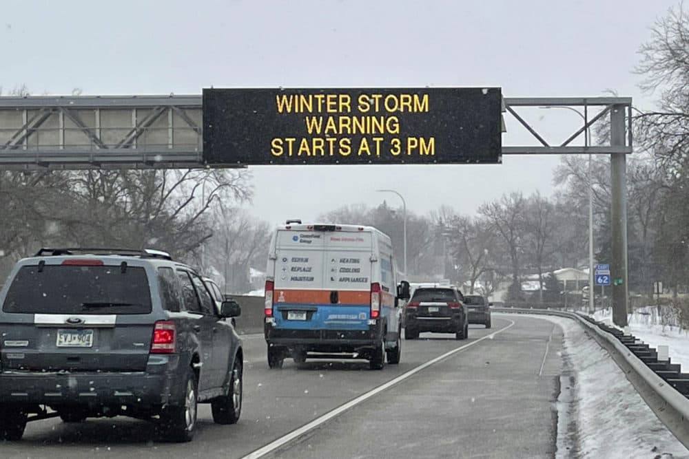 Vehicles pass a sign that reads "WINTER STORM WARNING STARTS AT 3PM" along Interstate Highway 35 near the Minneapolis-Saint Paul International Airport. (Trisha Ahmed/AP)