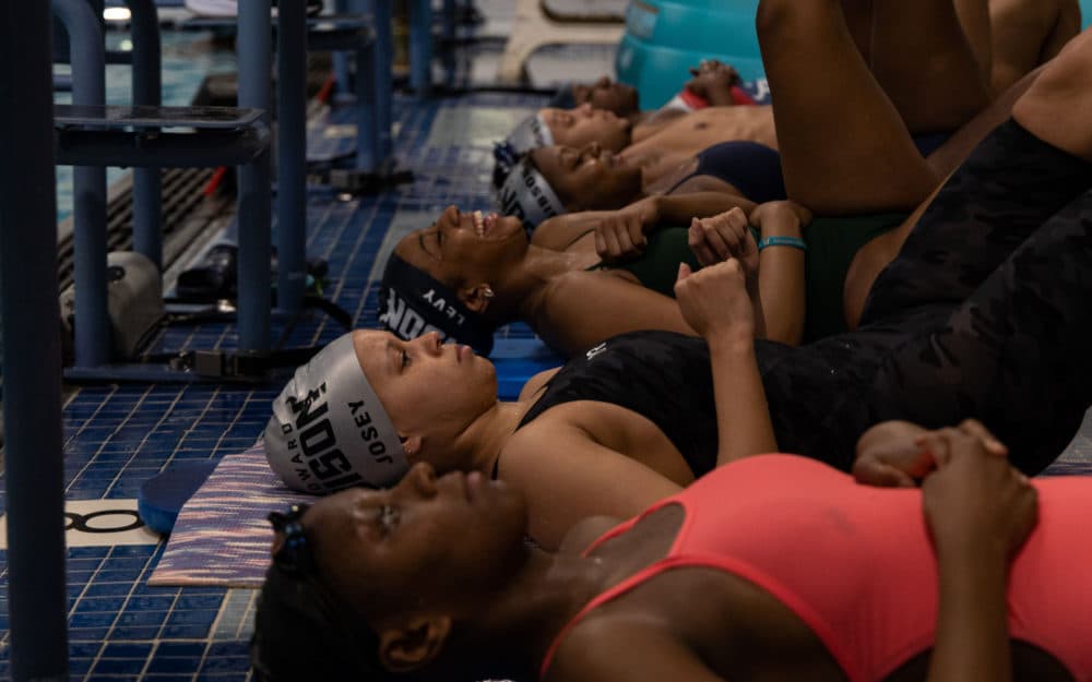  Members of Howard University's swim team lay down by the pool to warm up. (Devin Speak for Here &amp; Now)