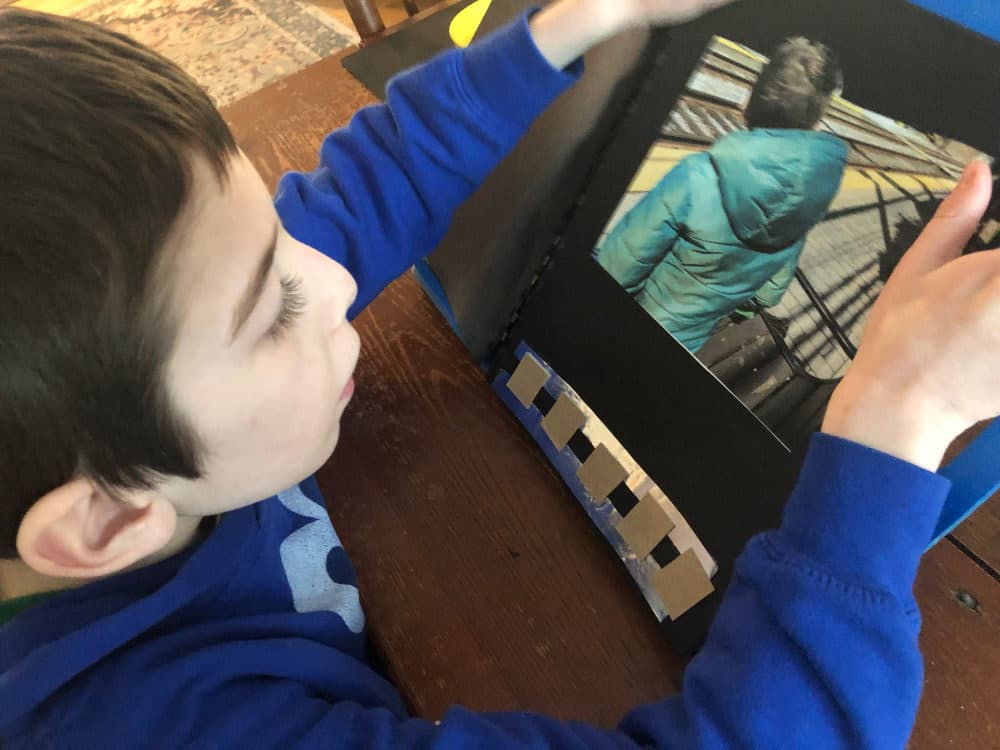Henry is reading an adapted book (both print and Braille) about T that his visually impaired teacher made for him.  (Courtesy Rachel Bennett)