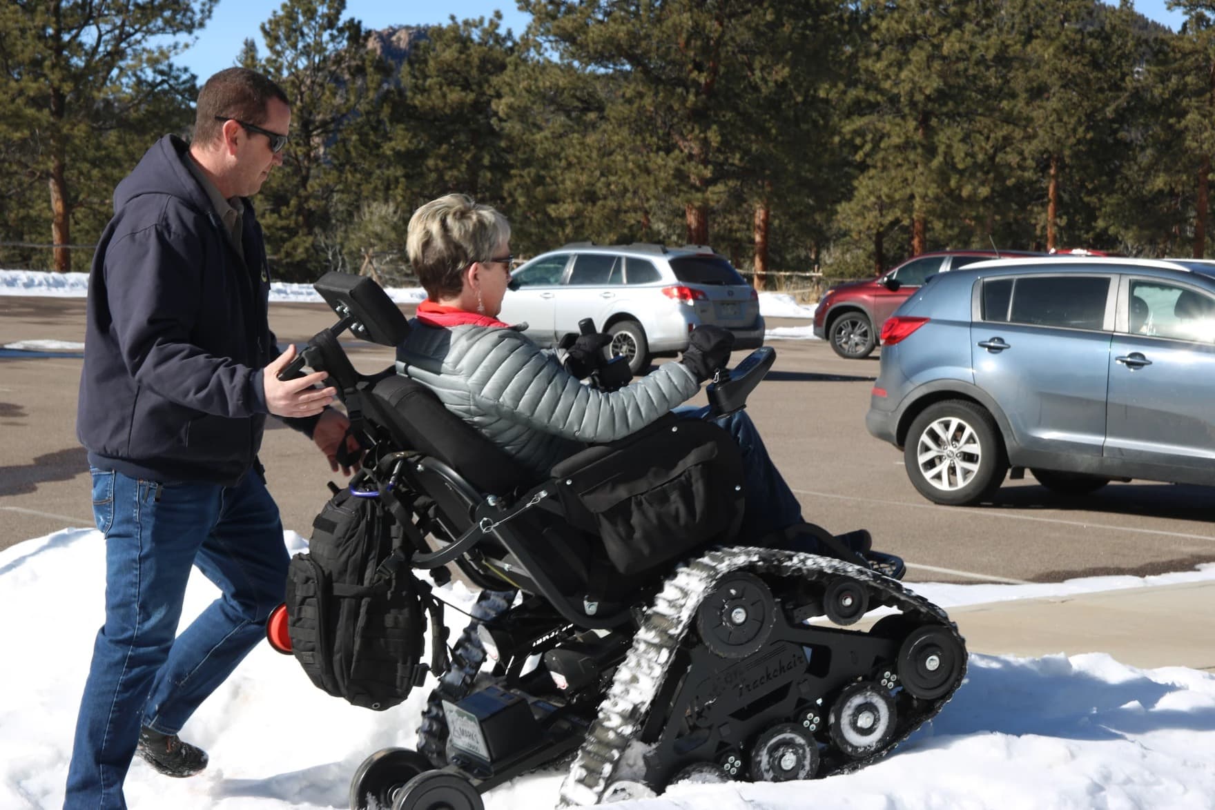 Park manager Zach Taylor helps push Lisa Willman over a snow pile at Staunton State Park in Pine, Colorado. (Emma VandenEinde/KUNC)