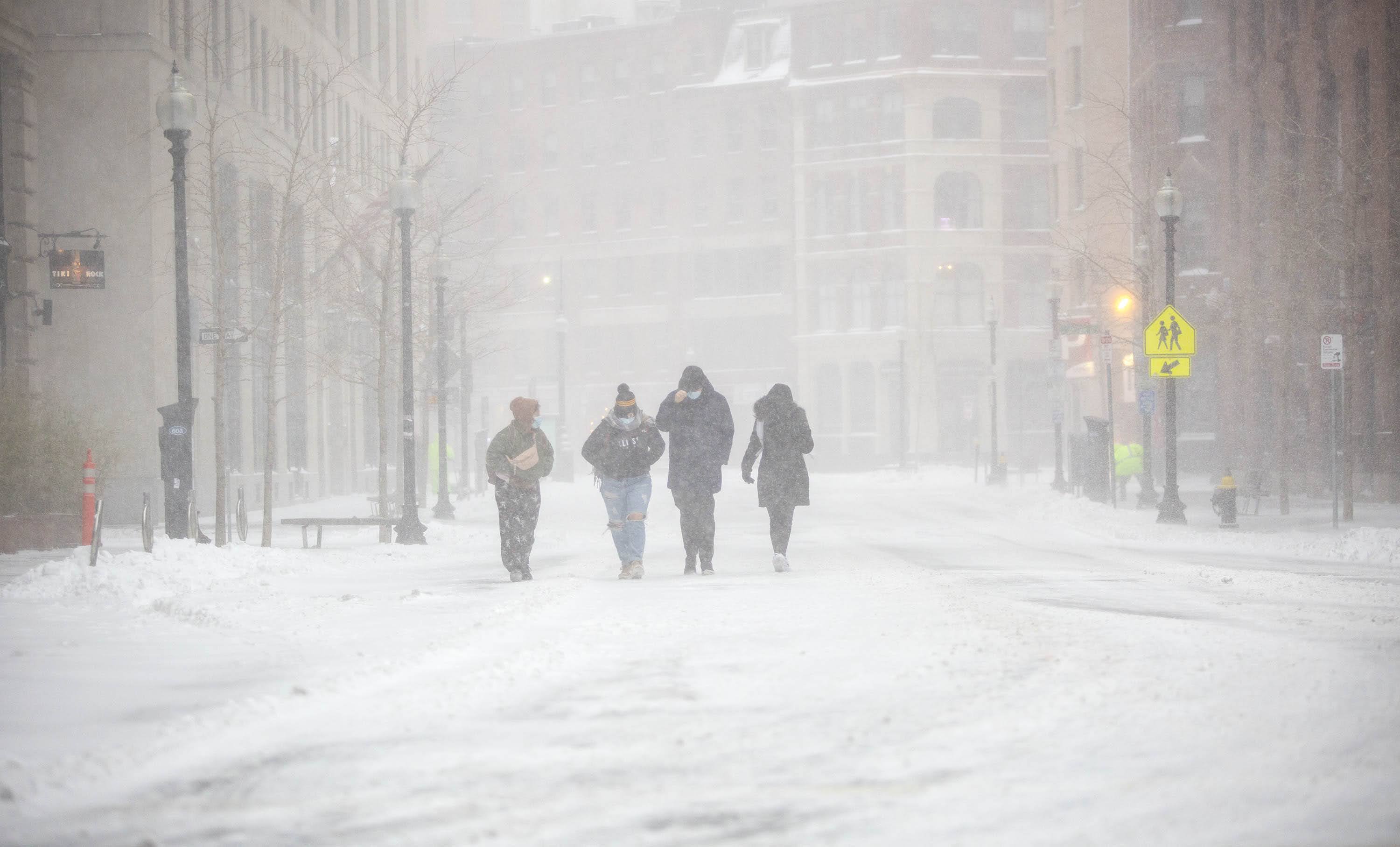 A group of people battle with wind and snow as they make their way along Broad Street. (Robin Lubbock/WBUR)