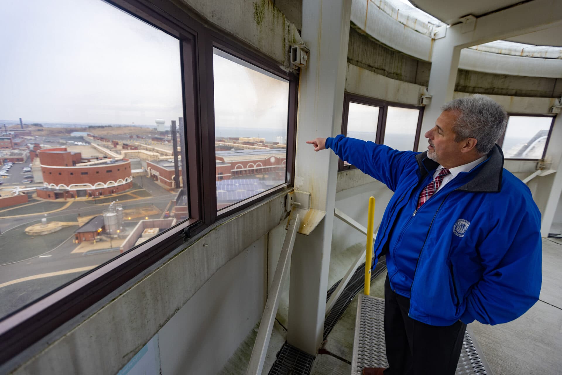 David Duest, director of Deer Island Wastewater Treatment Plant, points toward the facility. (Jesse Costa/WBUR)