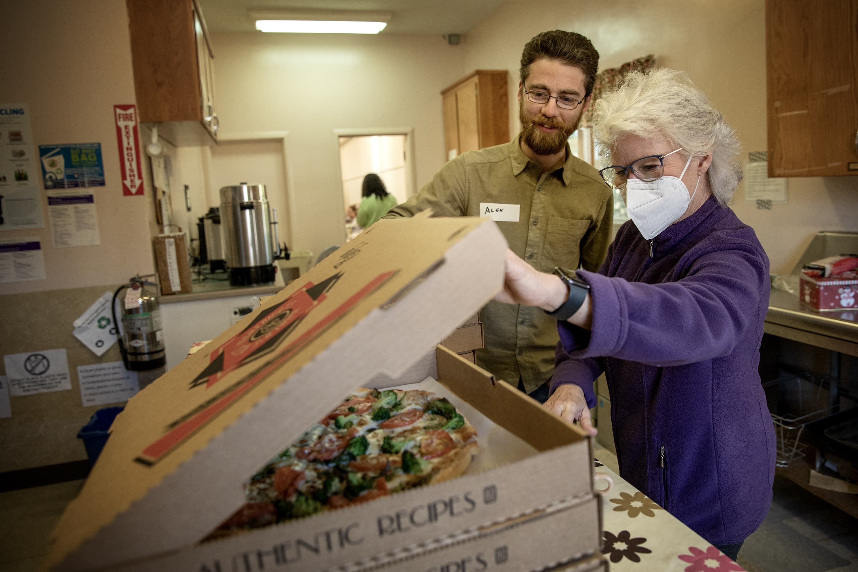 Framingham Repair Cafe organizers Alex Volfson and Marybeth Croci open pizzas brought in for repair volunteers. (Robin Lubbock/WBUR)