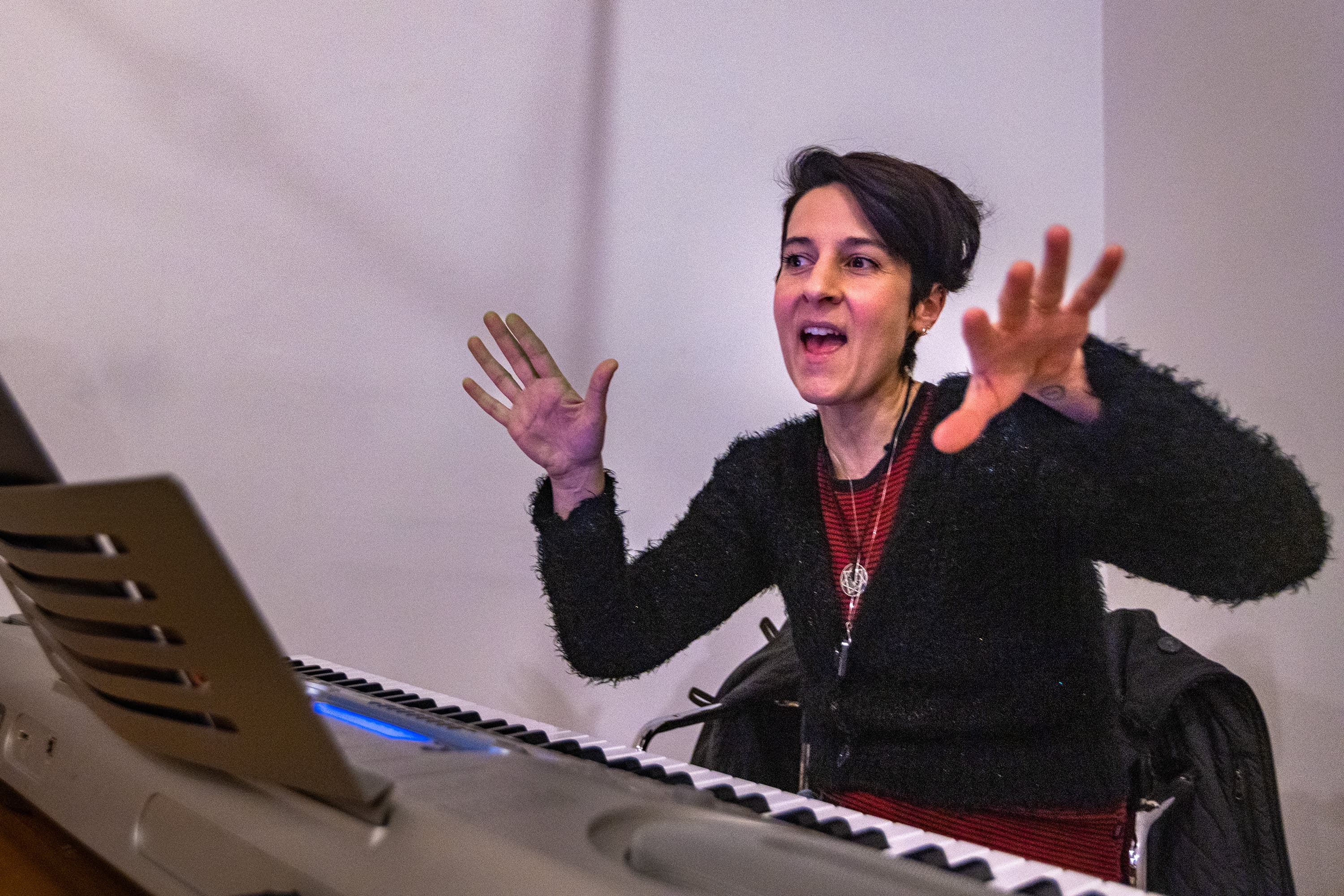 Composer Melissa Carubia directs the cast through one of the numbers in “T: An MBTA Musical” during a rehearsal at the Somerville Armory. (Jesse Costa/WBUR)